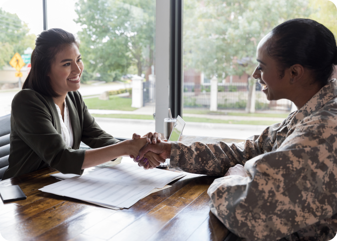 A man in military fatigues shakes hands with a woman.