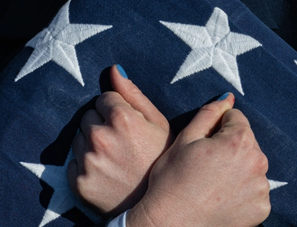 Two hands crossed over a blue banner of white stars.